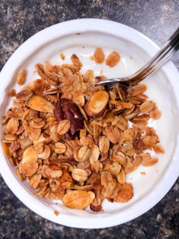 toasted granola with pecans and almonds on a cup of yogurt