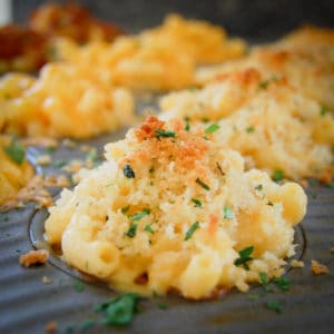 close up view of mac and cheese cup with bread crumb topping in muffin pan