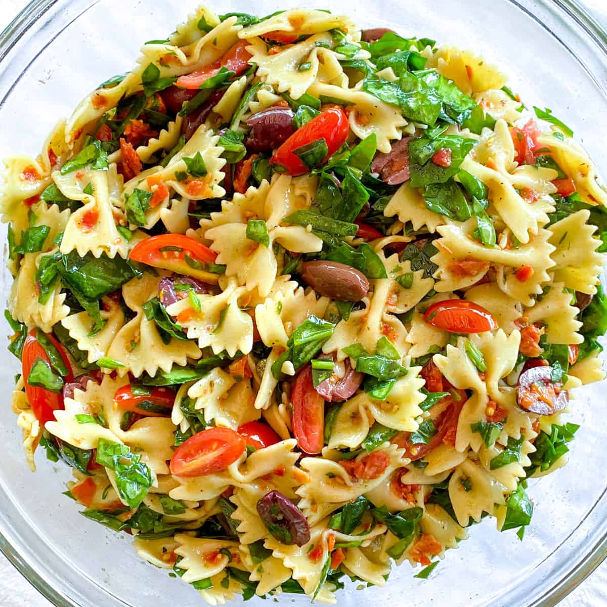 colorful bow tie pasta salad with fresh tomatoes, sun dried tomatoes, kalamata olives, and chopped spinach