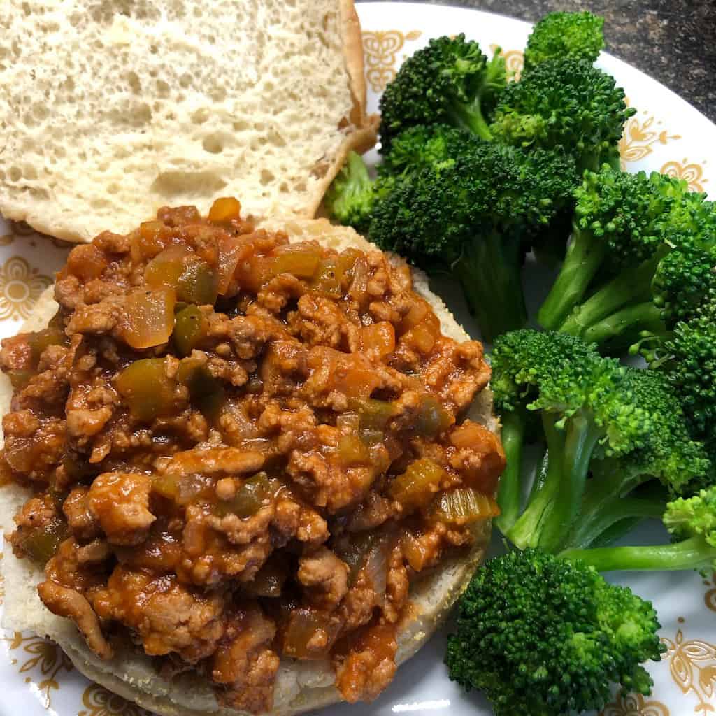 open faced bun with turkey sloppy joe and steamed broccoli on plate