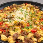 southwest breakfast skillet of browned sausage, scrambled eggs, chopped peppers and onions, topped with melted shredded cheese