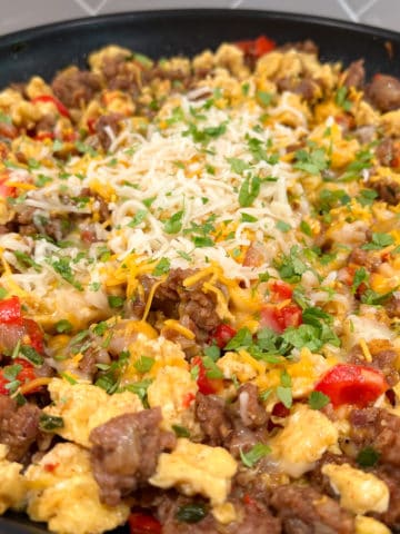 southwest breakfast skillet of browned sausage, scrambled eggs, chopped peppers and onions, topped with melted shredded cheese