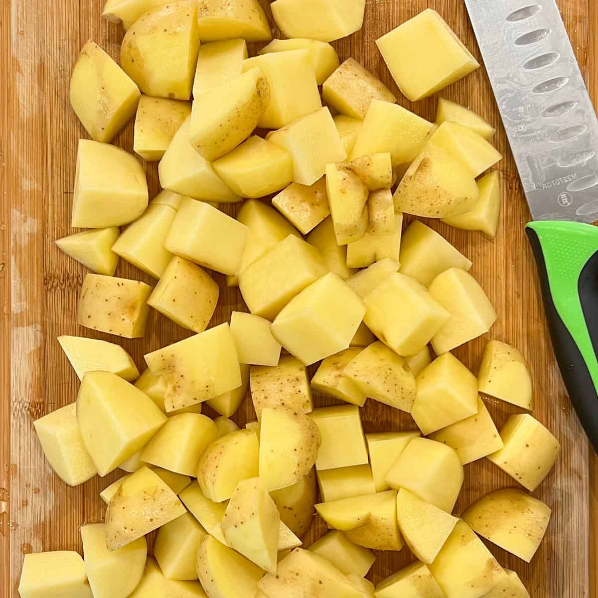 large diced yukon gold potatoes on cutting board with chef's knife