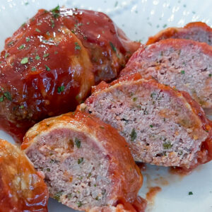 bacon wrapped mini meatloaf sliced on plate