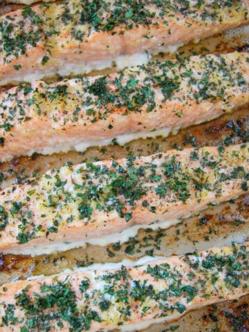 slices of baked salmon with minced garlic and parsley