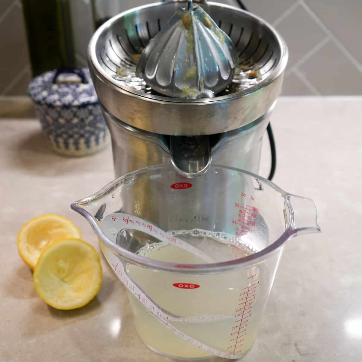 electric citrus juicer with lemon juice and water in measuring cup
